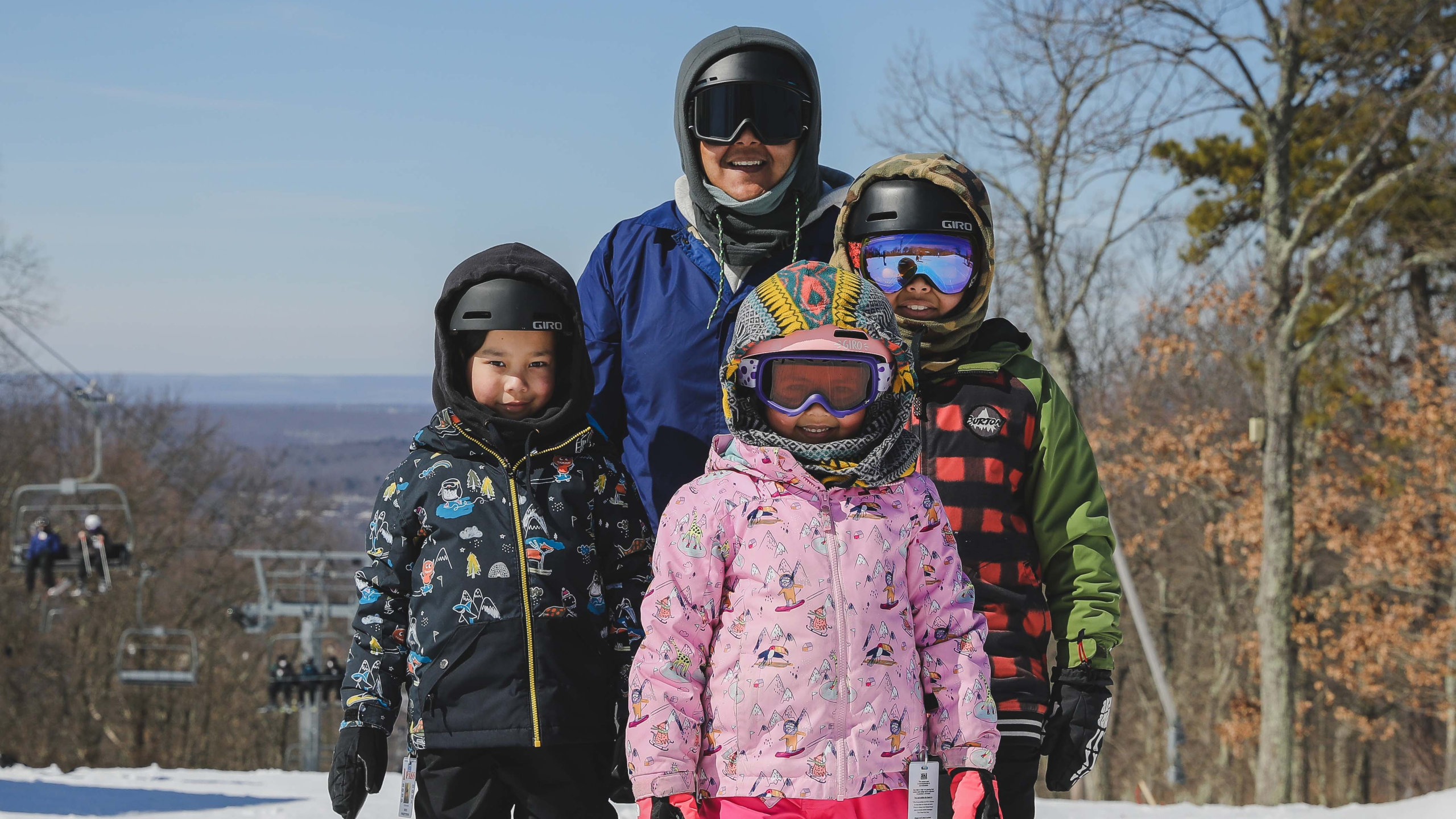 A family of four smiling at the top of the mountain