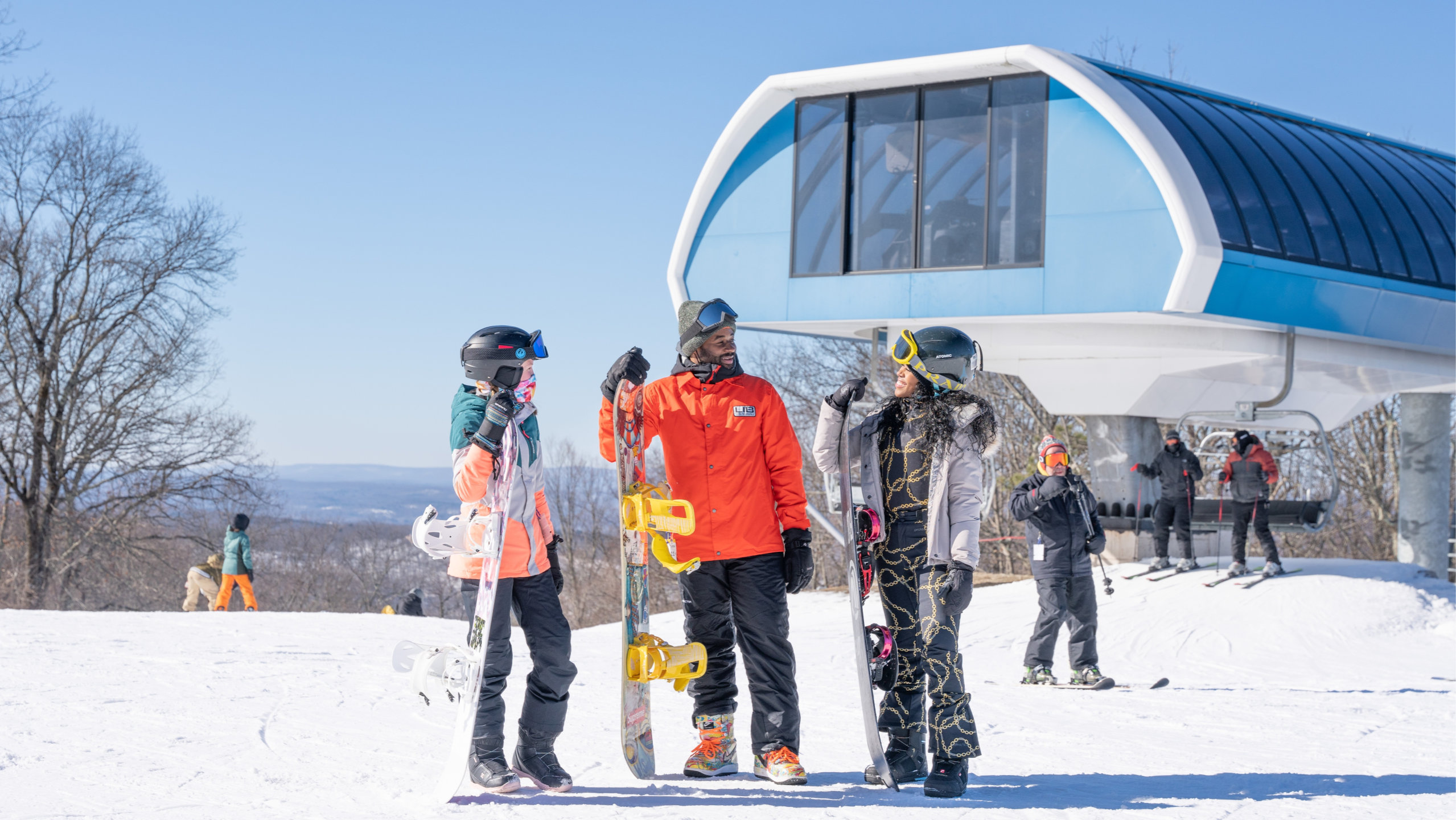 three snowboarders at the top of the lift