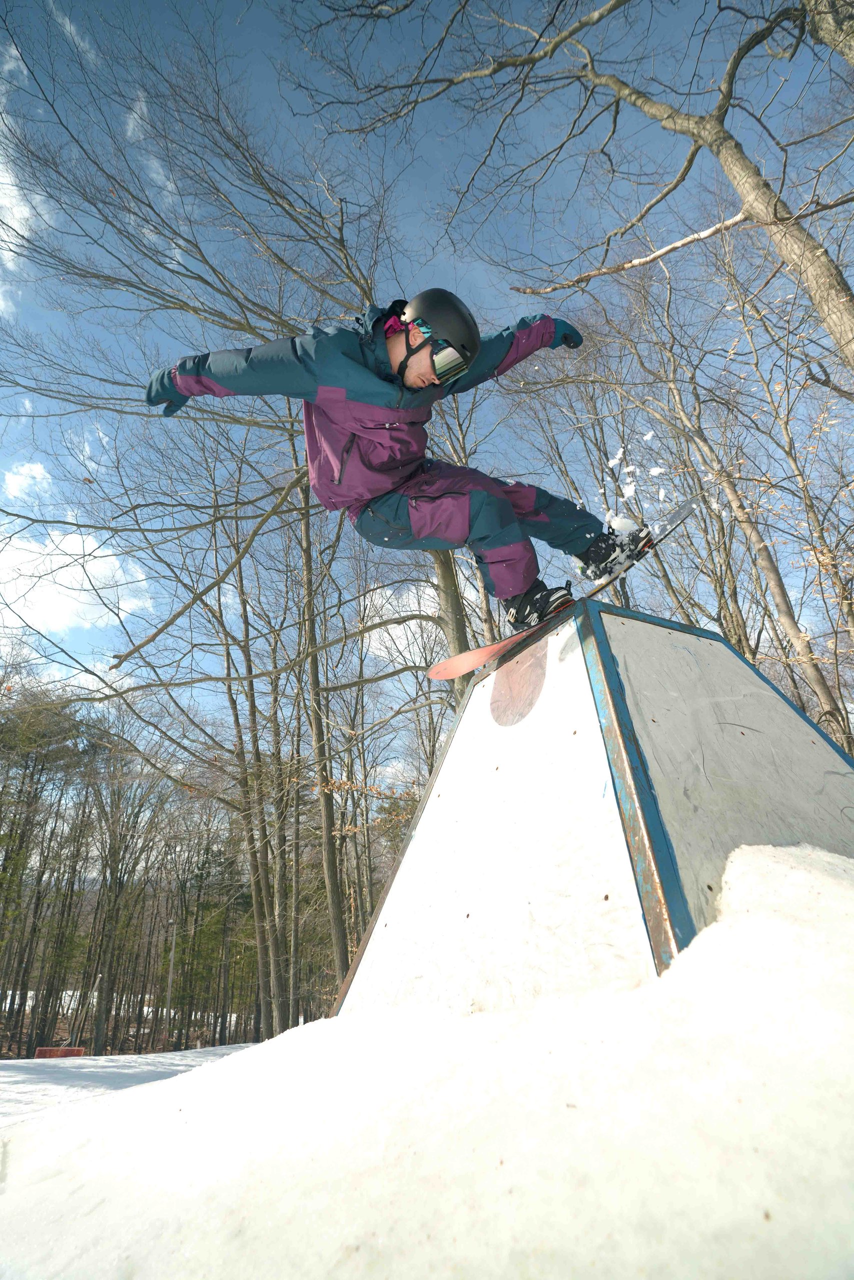 Snowboarder doing a box jump trick that looks like a pyramid
