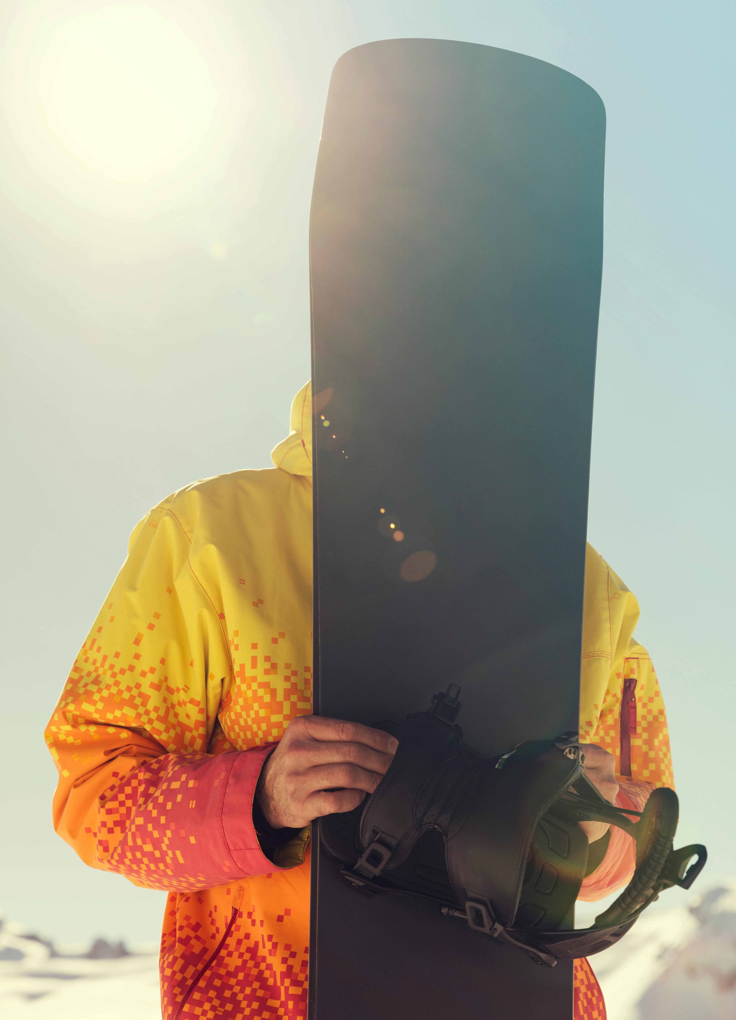pexels-joel-super-188959-2071654 Man covering face with snowboard wearing a yellow and orange jacket