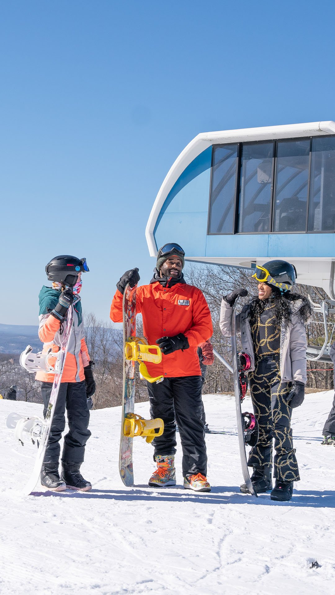 3 snowboarders holding a snowboard by the lift