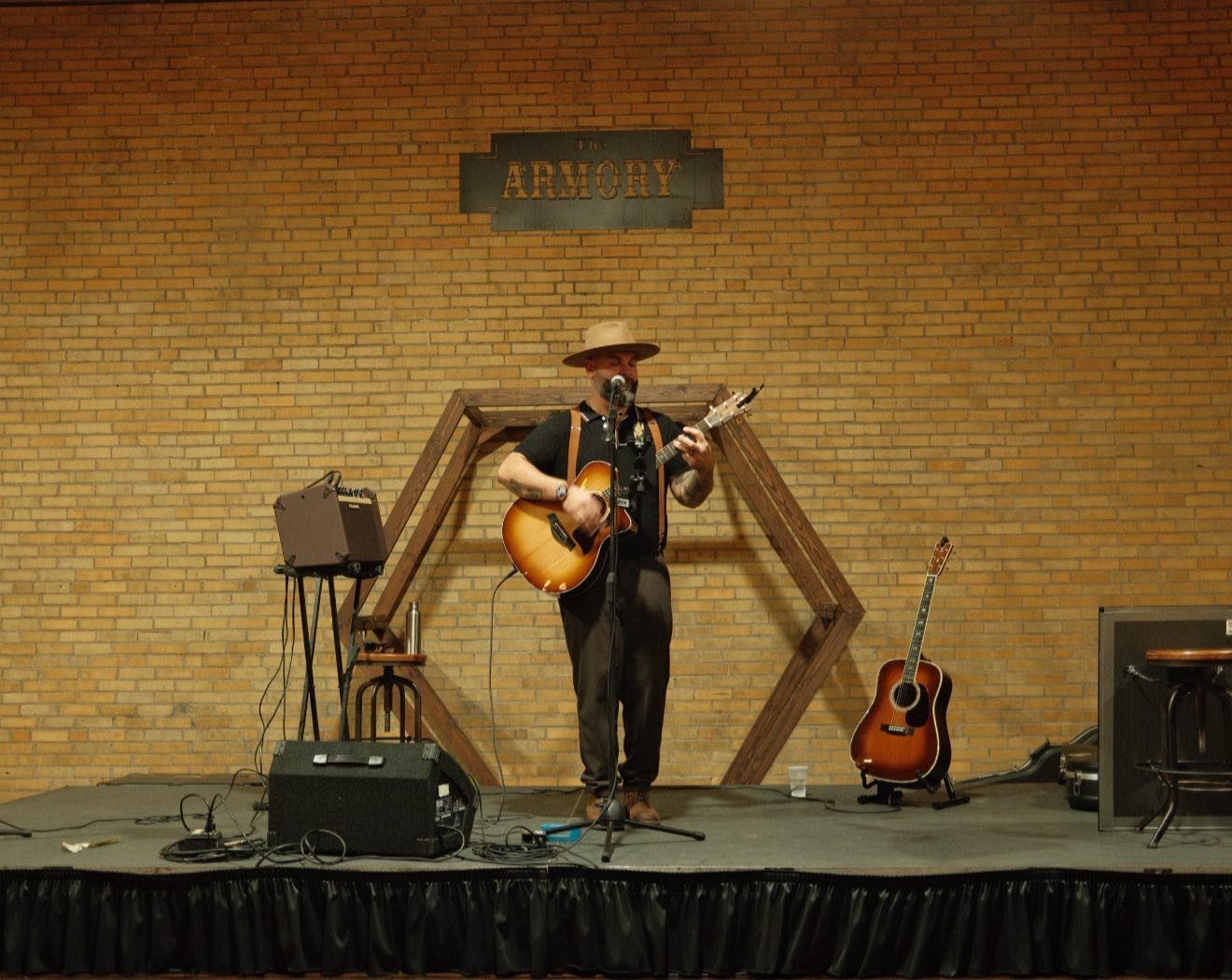 Guy singing with mic, guitar and a hat on