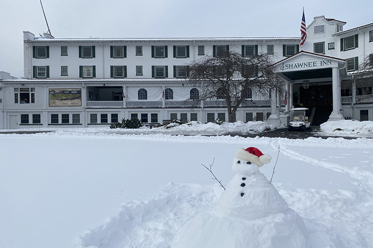 Large, white Shawnee Inn building with a snowman in front wearing a Santa hat.