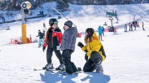 Ski instructor and children on snow.